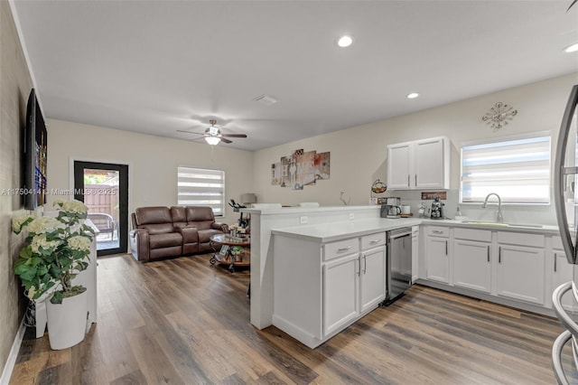 kitchen with light countertops, open floor plan, white cabinetry, dishwasher, and a peninsula