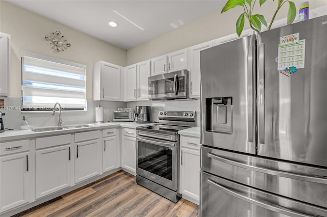 kitchen featuring a sink, stainless steel appliances, light countertops, and white cabinetry
