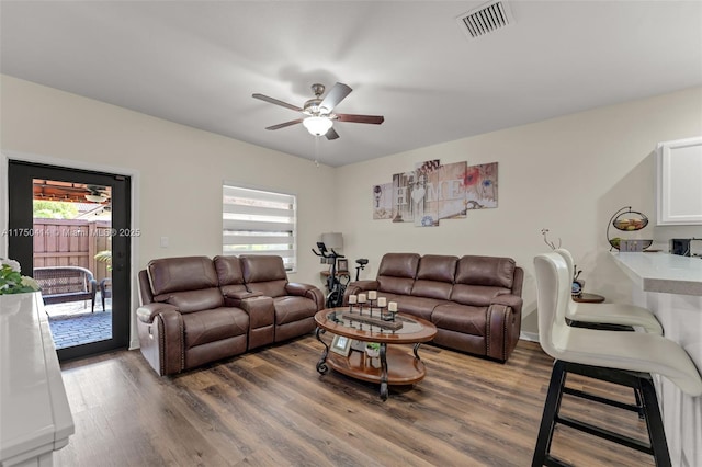 living area with dark wood-type flooring, a ceiling fan, visible vents, and a healthy amount of sunlight