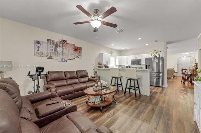living area with visible vents, arched walkways, ceiling fan, wood finished floors, and recessed lighting