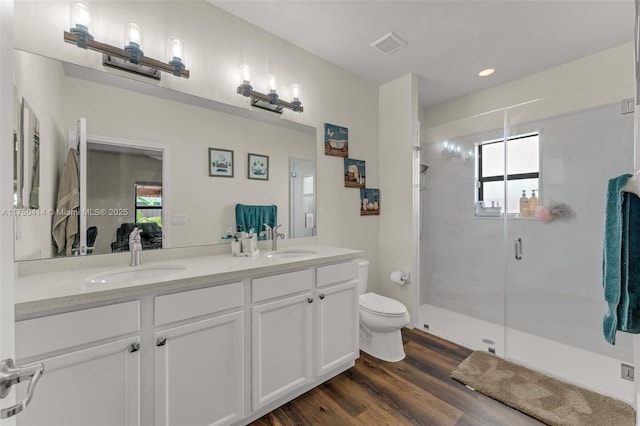 bathroom featuring a stall shower, double vanity, a sink, and wood finished floors
