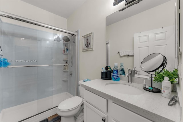 bathroom with vanity, a shower stall, and toilet