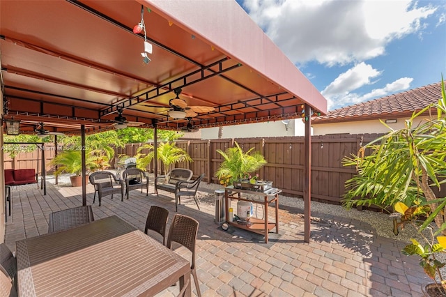 view of patio / terrace with outdoor dining area, a fenced backyard, and a ceiling fan