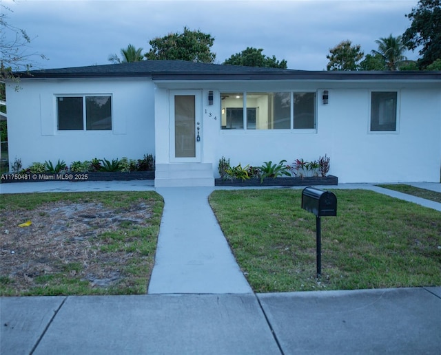 ranch-style home featuring a front yard and stucco siding