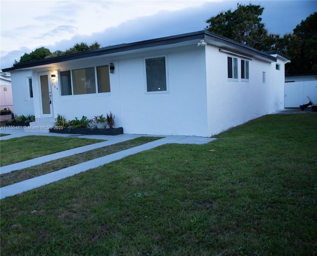 ranch-style home with a front yard and stucco siding