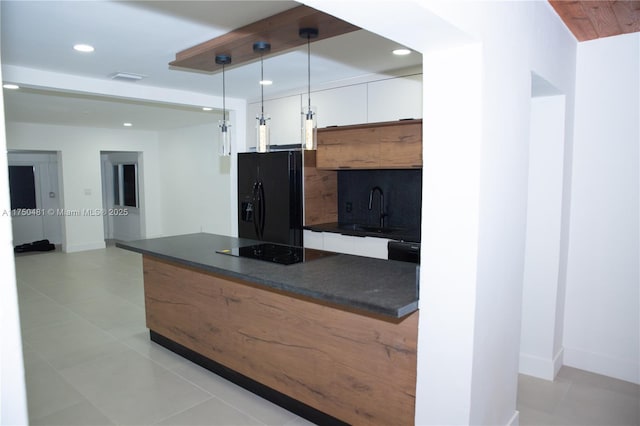 kitchen with a sink, white cabinetry, hanging light fixtures, black appliances, and dark countertops