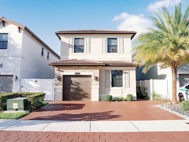 traditional-style home featuring a tiled roof, an attached garage, fence, decorative driveway, and stucco siding