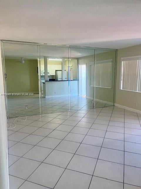 unfurnished bedroom with refrigerator, light tile patterned flooring, and baseboards