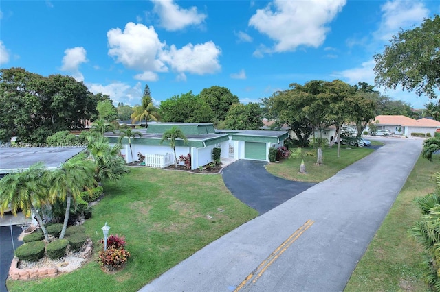 ranch-style house featuring a garage, aphalt driveway, and a front lawn