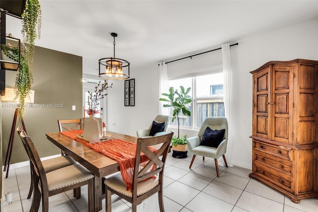 dining space featuring light tile patterned flooring, a notable chandelier, and baseboards