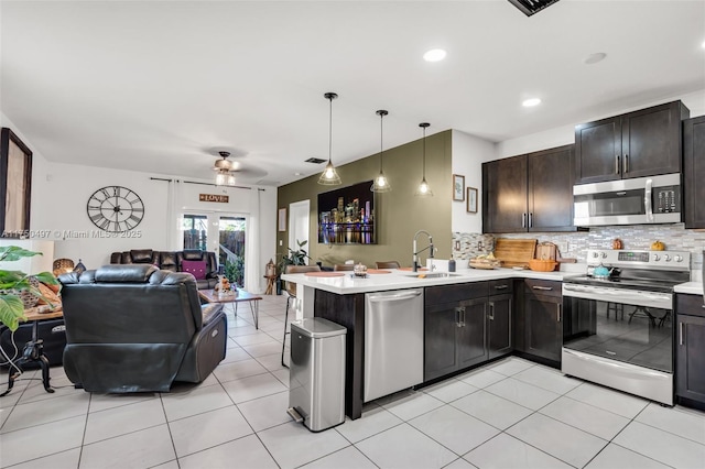 kitchen with open floor plan, a peninsula, light countertops, stainless steel appliances, and a sink