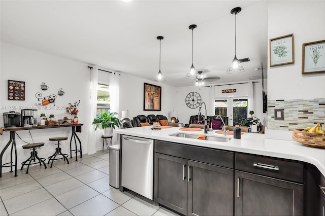 kitchen featuring dark brown cabinetry, a healthy amount of sunlight, light countertops, stainless steel dishwasher, and decorative light fixtures