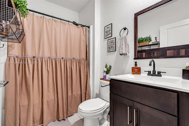 bathroom with toilet, a textured wall, and vanity