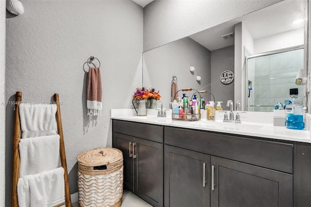 full bath featuring double vanity, a stall shower, visible vents, and a sink