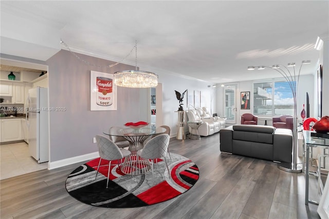 dining area with an inviting chandelier, crown molding, baseboards, and wood finished floors