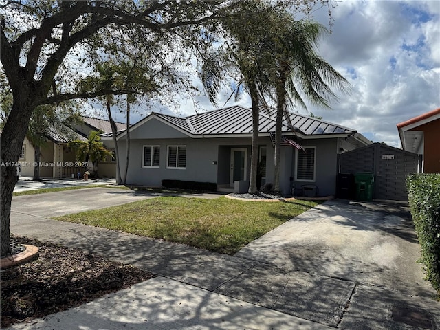 ranch-style house with metal roof, driveway, stucco siding, a front lawn, and a standing seam roof