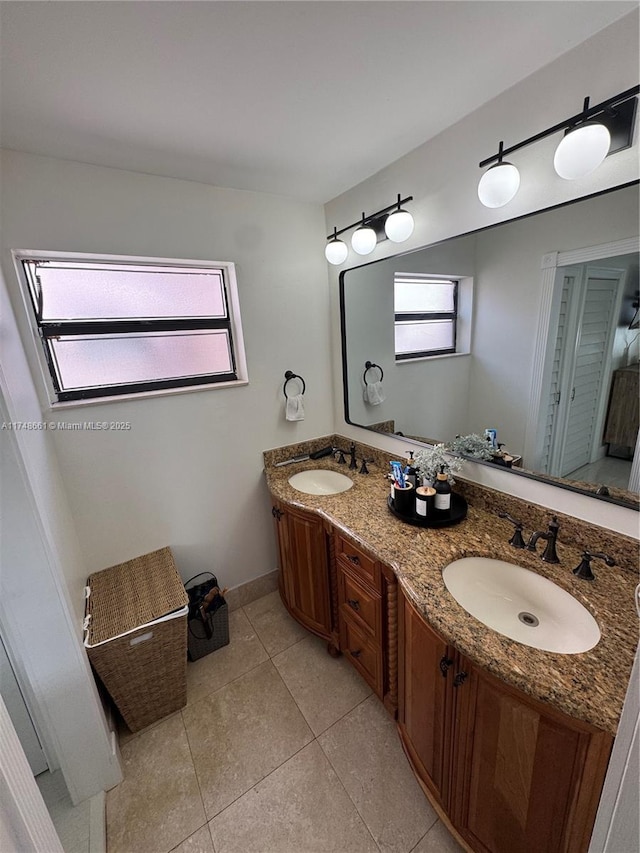 bathroom featuring tile patterned floors, a sink, baseboards, and double vanity