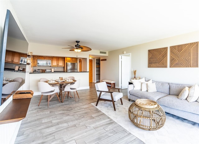 living room featuring a ceiling fan, visible vents, and light wood-style floors