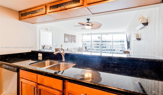 kitchen with a sink, dark stone countertops, open floor plan, and dishwasher