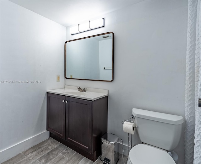 bathroom with baseboards, vanity, toilet, and wood finished floors