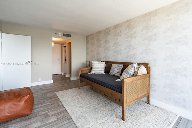 sitting room with baseboards, wood finished floors, visible vents, and wallpapered walls