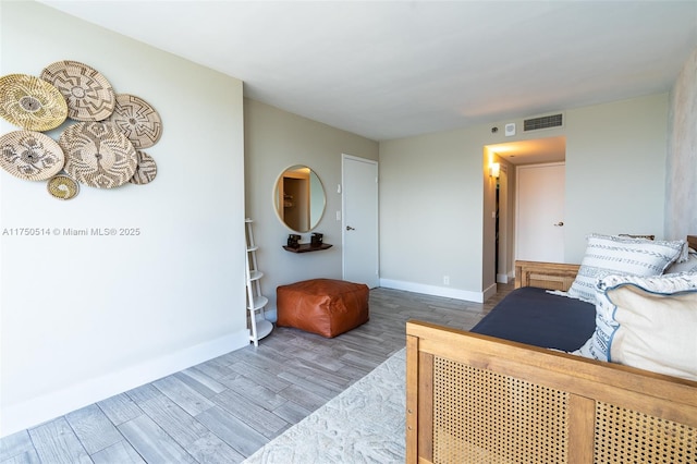 bedroom with wood finished floors, visible vents, and baseboards