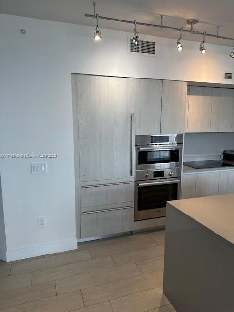 kitchen with light countertops, stainless steel double oven, visible vents, and wood finish floors