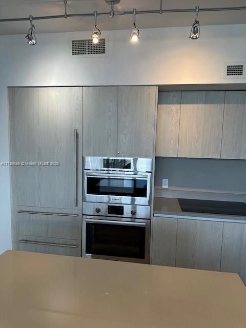 kitchen with light countertops, visible vents, stainless steel double oven, and modern cabinets