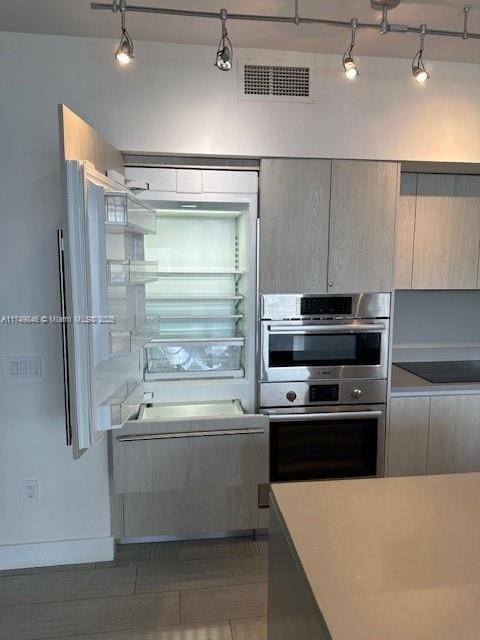 kitchen with stainless steel double oven, light countertops, visible vents, and modern cabinets