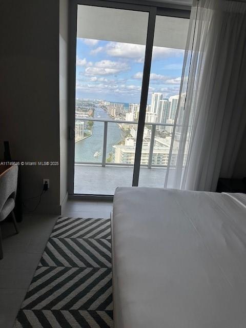 bedroom with a water view, multiple windows, and a city view