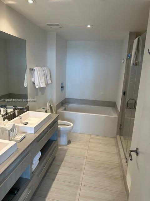 bathroom featuring double vanity, a stall shower, toilet, a bath, and a sink