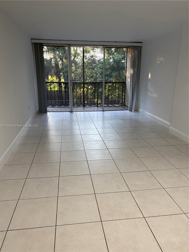 unfurnished room with light tile patterned floors, baseboards, and floor to ceiling windows