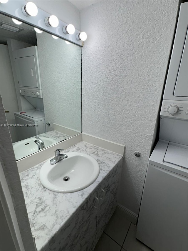 bathroom with tile patterned flooring, stacked washer and clothes dryer, and a textured wall