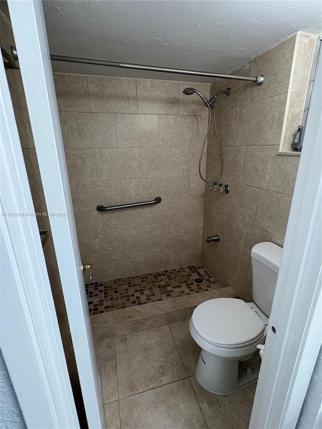 full bathroom featuring a stall shower, tile patterned flooring, and toilet