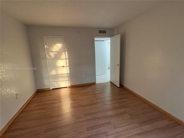 spare room with visible vents, a textured wall, baseboards, and wood finished floors