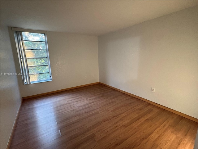 unfurnished room with baseboards and wood finished floors