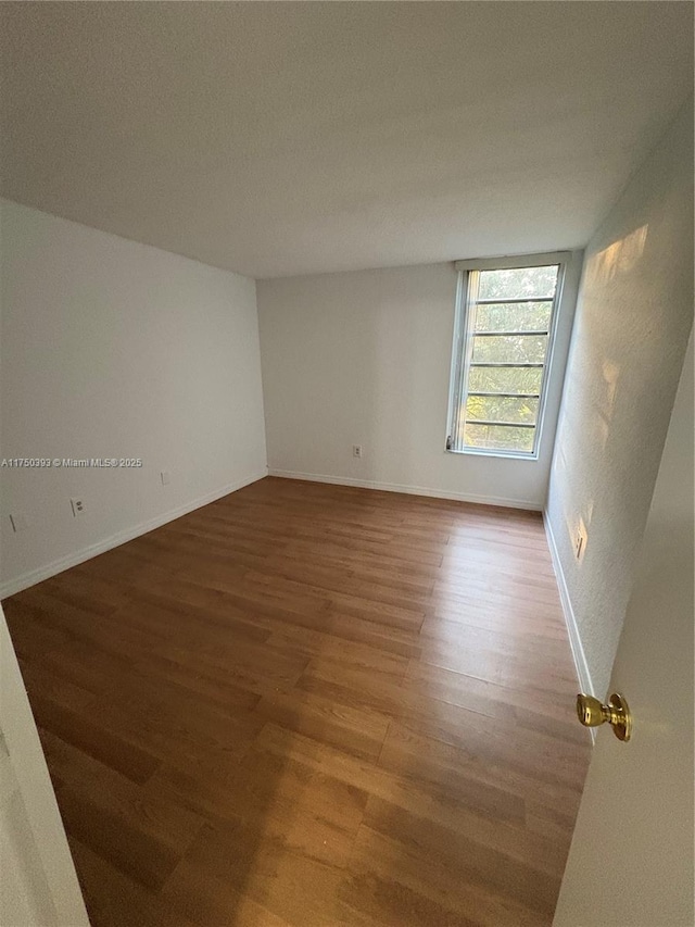 unfurnished room with baseboards and wood finished floors