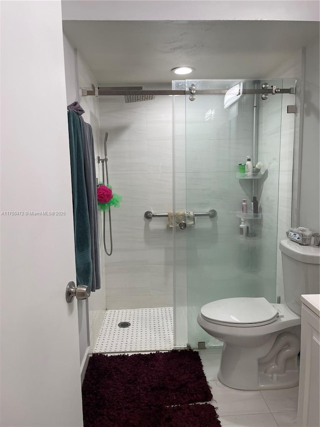 bathroom featuring vanity, toilet, tile patterned floors, and a stall shower