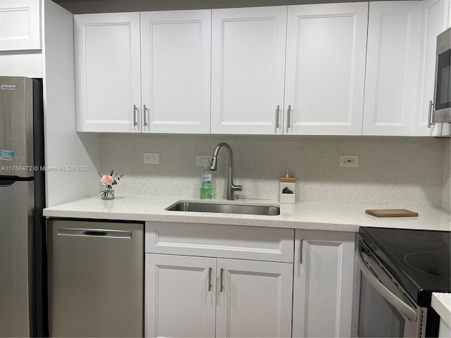 kitchen featuring white cabinets, stainless steel appliances, a sink, and light countertops