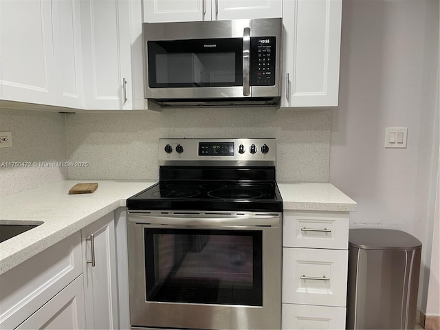 kitchen featuring light stone counters, appliances with stainless steel finishes, backsplash, and white cabinets