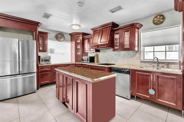 kitchen featuring stainless steel appliances, glass insert cabinets, a kitchen island, and dark brown cabinets