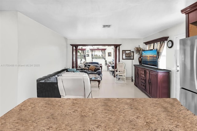 kitchen featuring reddish brown cabinets, visible vents, open floor plan, and freestanding refrigerator