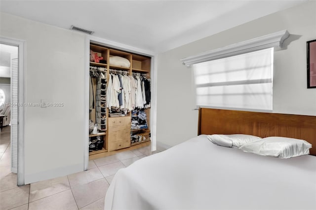 bedroom with a closet, visible vents, multiple windows, and light tile patterned flooring