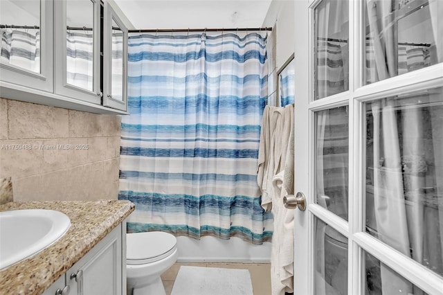 bathroom with tile walls, shower / bathtub combination with curtain, toilet, vanity, and tile patterned flooring