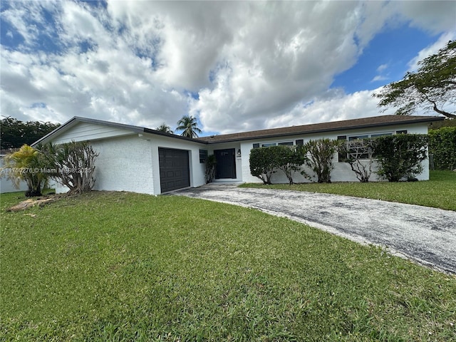 single story home with a garage, a front yard, brick siding, and driveway