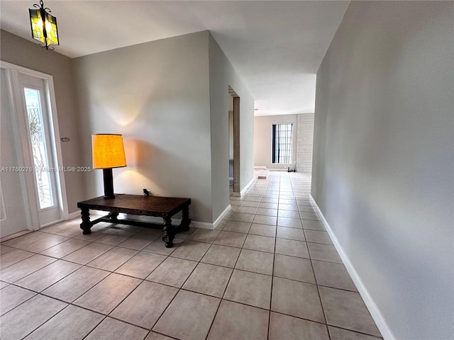 corridor with baseboards and light tile patterned floors