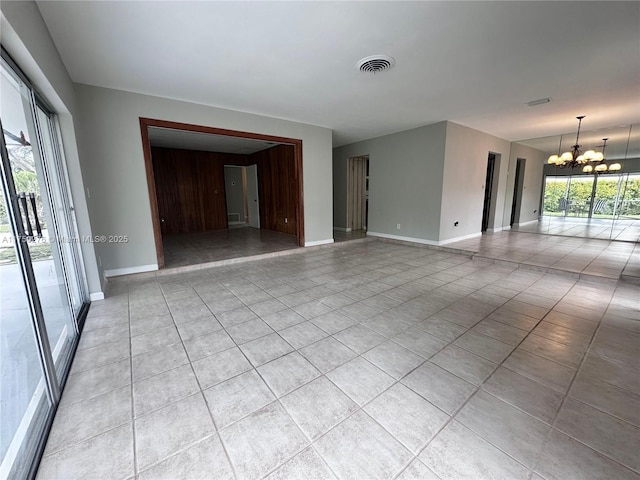 empty room with a chandelier, light tile patterned flooring, visible vents, and baseboards