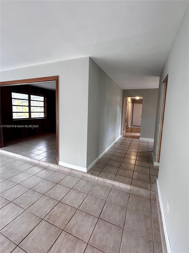 hall featuring light tile patterned floors and baseboards