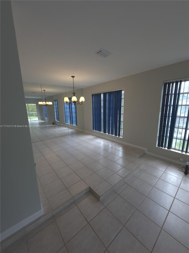 unfurnished room with light tile patterned flooring, a notable chandelier, visible vents, and baseboards