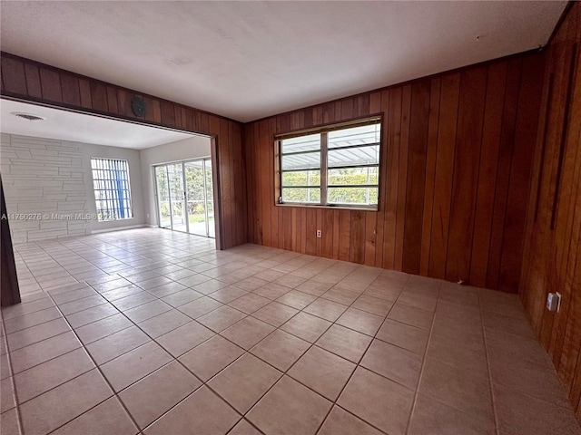 empty room with light tile patterned flooring and wooden walls